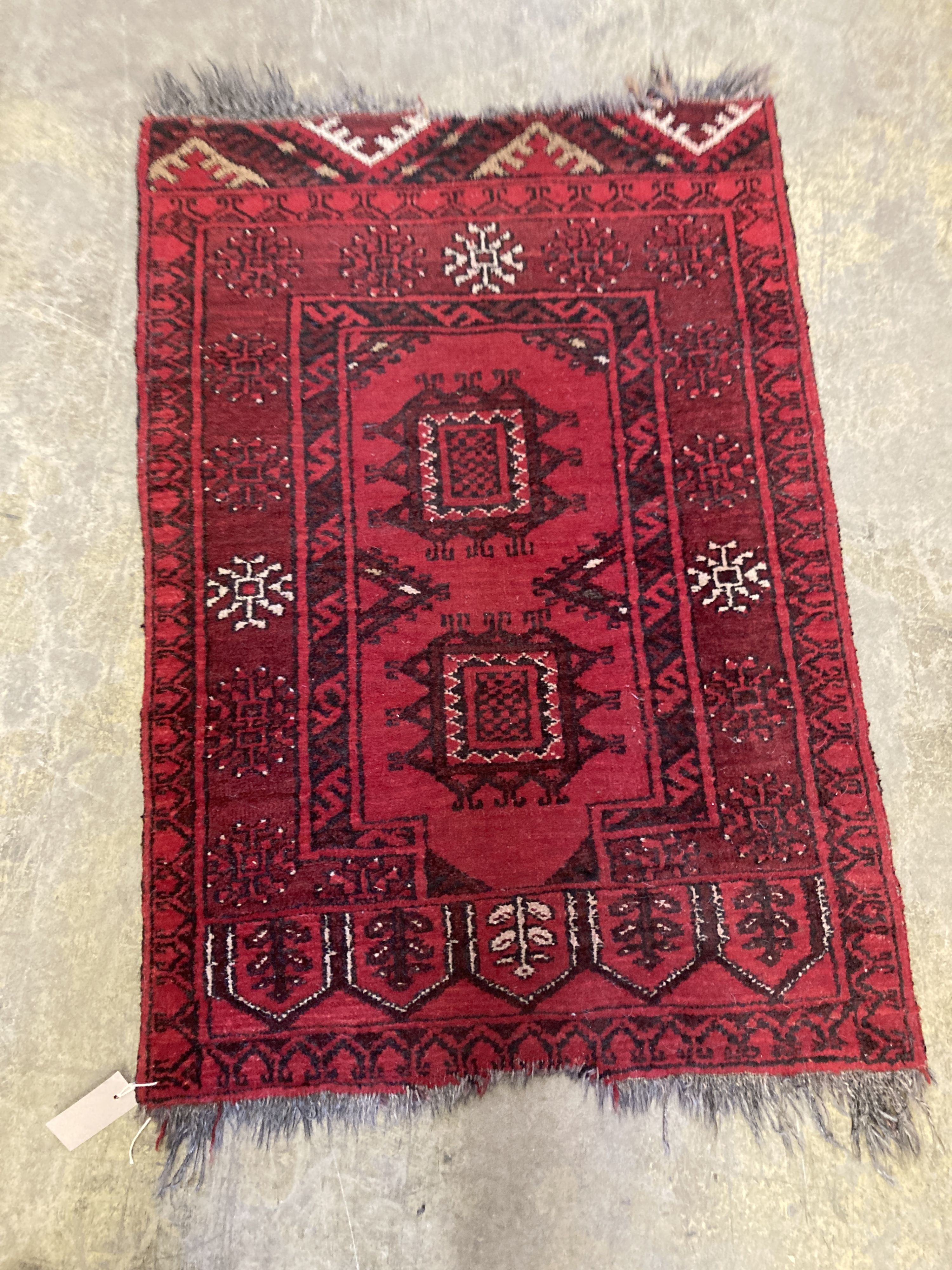 An Afghan red ground rug with stylised mihrab and iris motifs, a small Afghan rug and three carpet panel cushion covers, largest 200 x